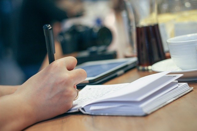 Photographie einer Person die Notizen in einem Meeting festhält